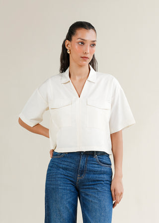 Cropped V-Neck Shirt – WS25-199 for Women – Summer Reverie Collection | KOA | Shop Online.
Woman wearing a white short-sleeve shirt and blue jeans against a plain background