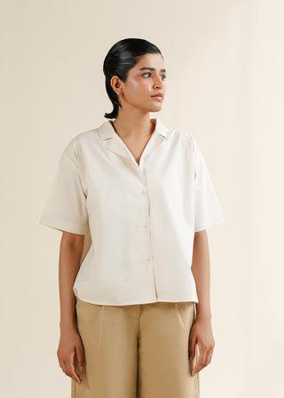 Notch Collar Shirt – WS25-163 for Women – Summer Reverie Collection | KOA | Shop Online.
Woman wearing a beige short-sleeve shirt and beige pants against a plain background