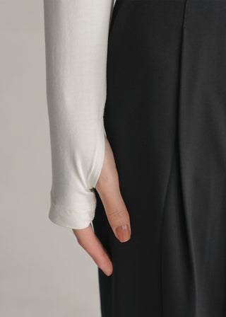 Close-up of a hand wearing a white sleeve with a black Tailored Wide Leg Pleated Pant in the background - KOA