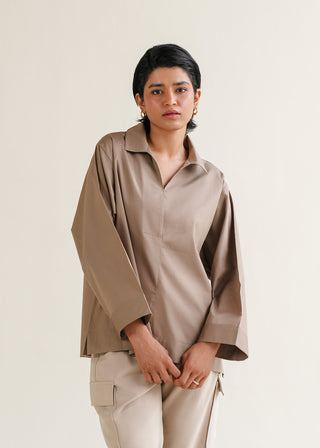 Basic Cotton Blouse – WS25-155 for Women – Summer Reverie Collection | KOA | Shop Online.
Women wearing a beige shirt with a wide collar and long sleeves on a plain background