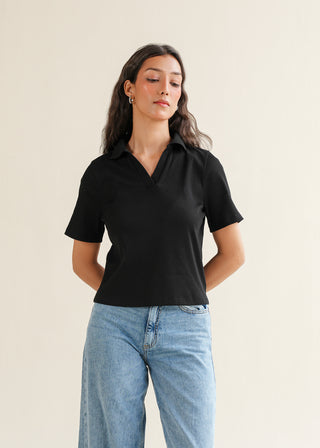 Popover Shirt – WS25-184 for Women – Summer Reverie Collection | KOA | Shop Online.
A woman modeling a relaxed-fit black popover shirt with a V-placket and short sleeves, paired with blue jeans.