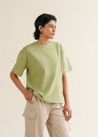 Cotton T-shirt – WS25-181 for Women – Summer Reverie Collection | KOA | Shop Online.
Woman wearing a light green t-shirt and beige pants against a plain background