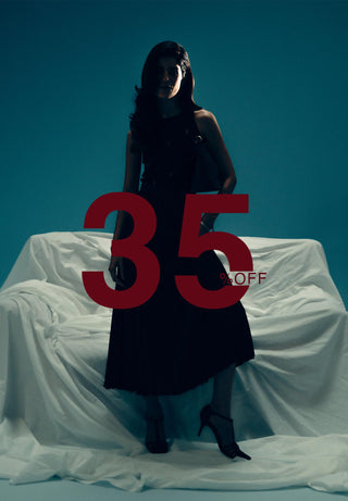Woman in a black dress sitting on a white draped couch with a large red '35' off sign.